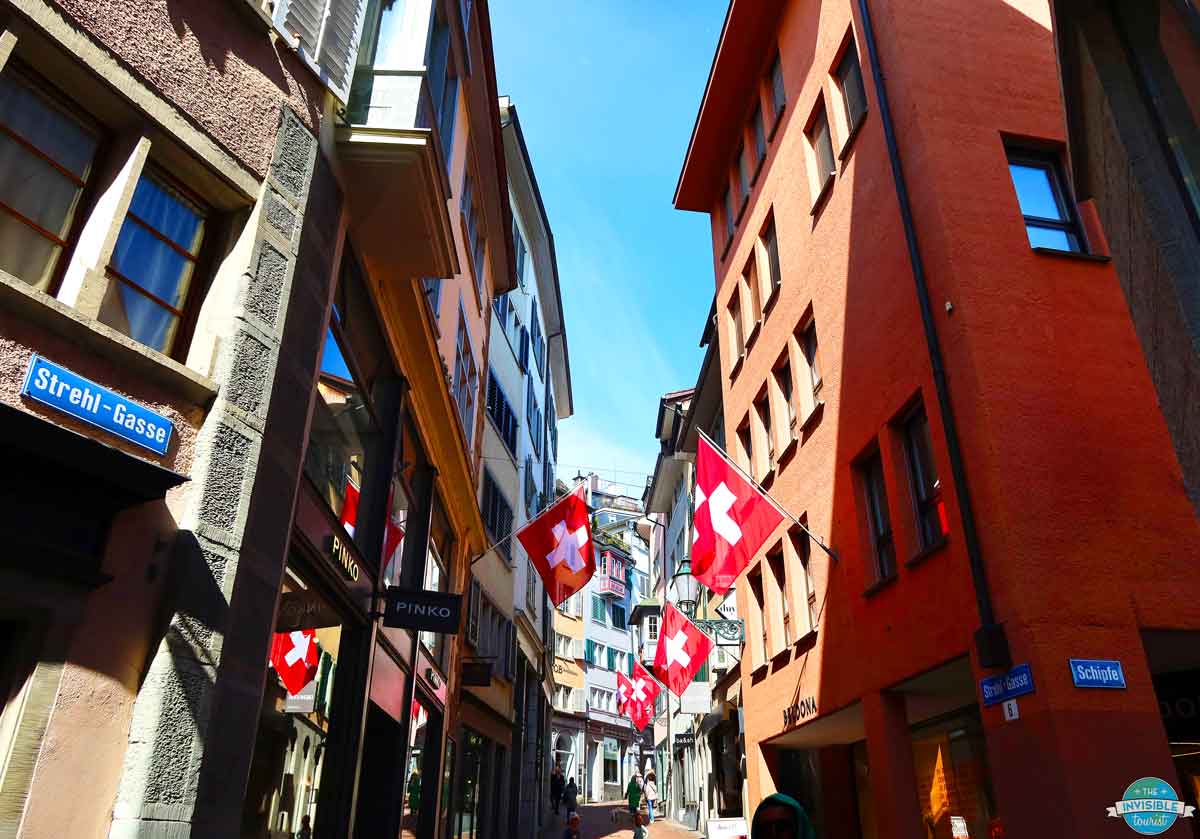 Swiss flags hanging above Strehlgasse in Zurich Old Town, Switzerland | The Invisible Tourist