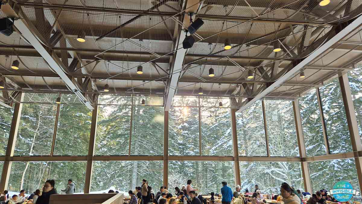 Breakfast buffet restaurant with tall windows overlooking snowy forest at Risonare Tomamu