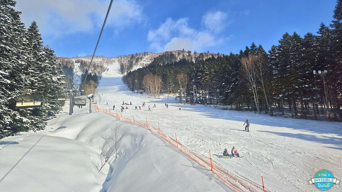 Chairlift with no queue over a wide groomed run at Tomamu ski resort