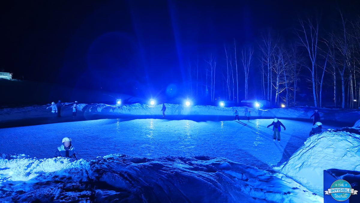 Ice skaters on the blue lit rink at the Tomamu Ice Village at night