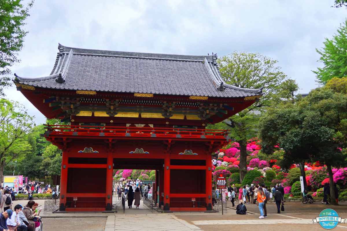 The two-storey Romon tower gate at Nezu Shrine in Tokyo, with azaleas blooming beside it