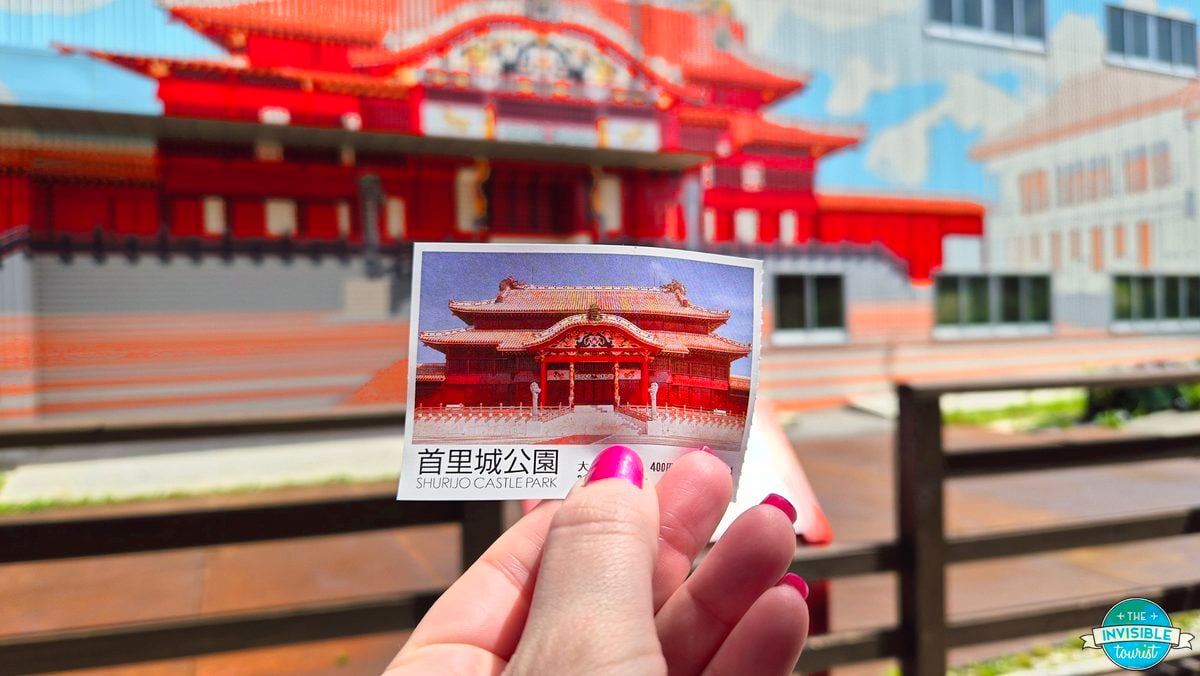Holding a Shurijo Castle Park ticket in front of the main hall's temporary cover during the restoration, Naha