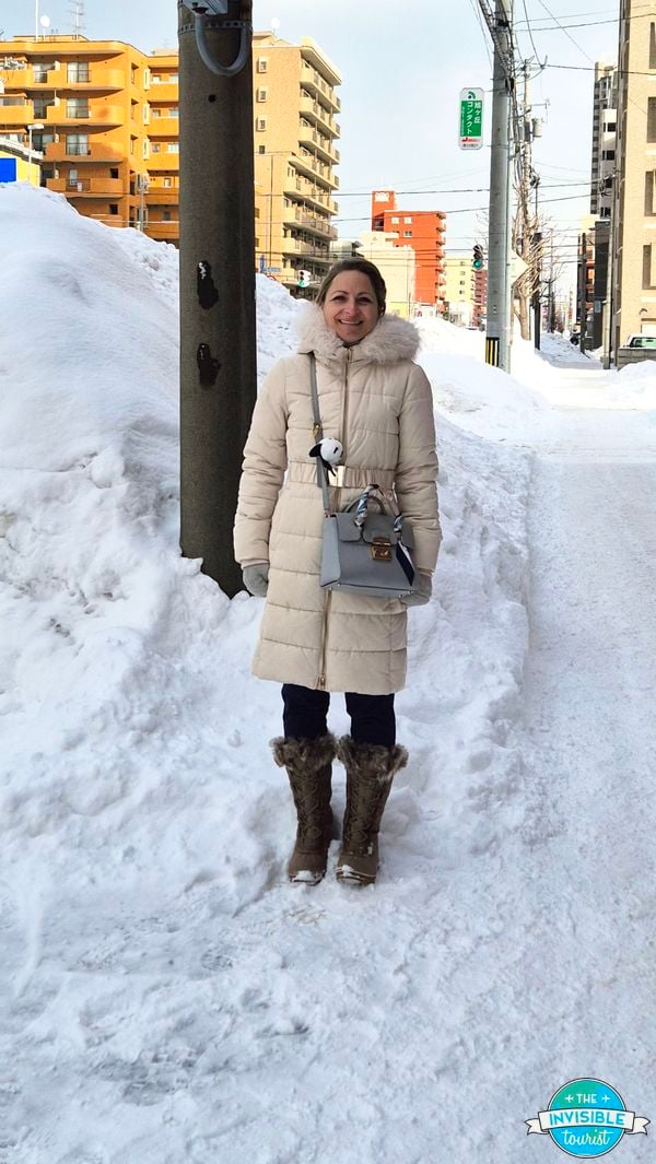 Alyse standing beside a pile of snow on a Sapporo street in January