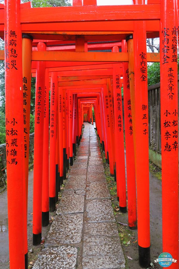An empty tunnel of vermilion torii gates leading to Otome Inari Shrine at Nezu Shrine, Tokyo, on a rainy day