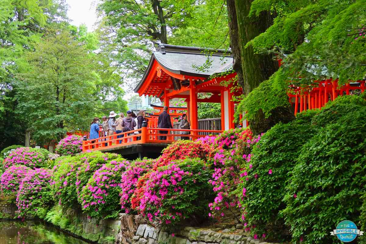 Visitors on a red shrine pavilion overlooking the azaleas and pond at Nezu Shrine, Tokyo
